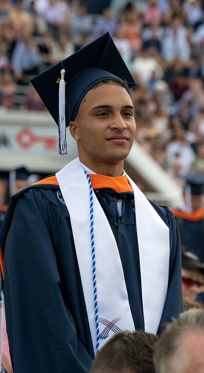 A student stands during èƵapp's commencement ceremony.
